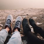 two person wearing pants and shoes sits on ground at daytime